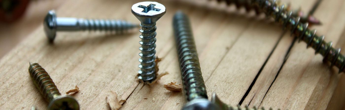 stock-photo-many-scattered-screws-one-of-them-screwed-into-the-wooden-plank-417279034
